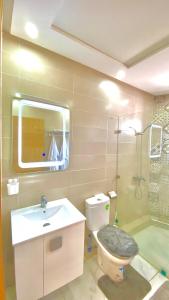 La salle de bains est pourvue de toilettes, d'un lavabo et d'un miroir. dans l'établissement superbe appartement climat Centralisé avec Jacuzzi supplémentaires, à Kenitra