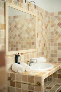 a bathroom with a sink and a mirror and towels at Hôtel Le Mas des Grès & Restaurant Sous les Platanes in Lagnes
