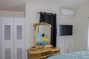 ein Schlafzimmer mit einem Spiegel und einer Kommode mit einem TV in der Unterkunft Little Paradise in Discovery Bay