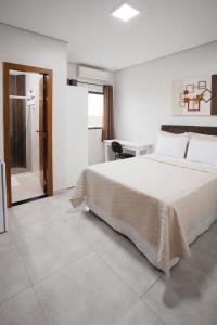 a bedroom with a large white bed and a desk at Hotel Kanaan in Pimenta Bueno