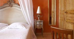a bedroom with a bed and a table with a lamp at Hôtel Le Mas des Grès & Restaurant Sous les Platanes in Lagnes