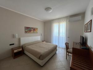 a bedroom with a bed and a desk and a television at Bikini Hotel in Vieste