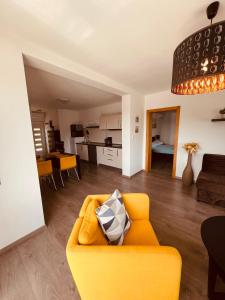 a living room with a yellow couch and a kitchen at Apartman Bijeca - Medulin in Medulin