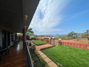 a balcony of a house with a green lawn at Sara green Valley Farm in Mahabaleshwar