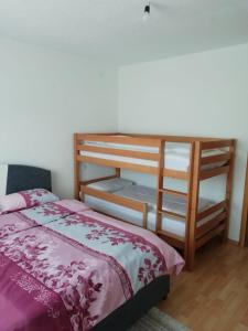 a bedroom with a bed and a wooden bunk bed at Apartman Bošnjak Ramsko jezero in Podbor