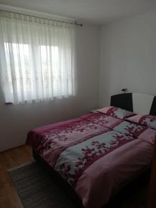 a bedroom with a bed and a window with curtains at Apartman Bošnjak Ramsko jezero in Podbor