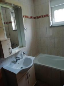 a bathroom with a sink and a mirror and a tub at Apartman Bošnjak Ramsko jezero in Podbor