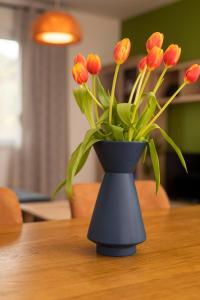 a black vase with orange tulips in it on a table at Downtown Labin in Labin