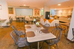 a conference room with tables and chairs and a screen at Pajuçara Praia Hotel in Maceió