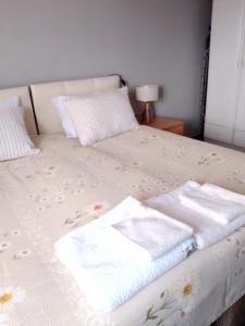 un letto con lenzuola bianche e asciugamani di Flat Close to Sea with Balcony in Seferihisar a Smirne