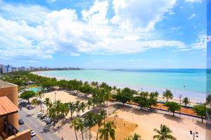 uma vista para uma praia com palmeiras e para o oceano em Pajuçara Praia Hotel em Maceió