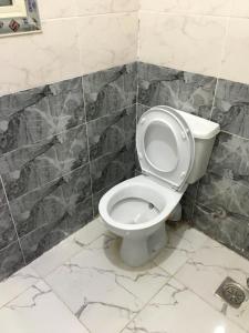 a bathroom with a white toilet in a tiled wall at استوديو in 6th Of October