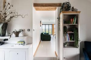 a room with white walls and a hallway with bookshelves at Willow Barn in Haddiscoe