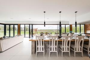a dining room with a large wooden table and white chairs at Willow Barn in Haddiscoe