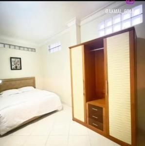 1 dormitorio con 1 cama grande y armario de madera en Flamboyan House en Padang