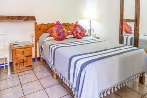a bedroom with a large bed with colorful pillows on it at Hotel Posada del Centro in Oaxaca City