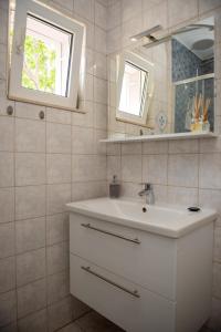 La salle de bains est pourvue d'un lavabo blanc et d'un miroir. dans l'établissement Apartment Fortuna - peacfull terrace, à Klis