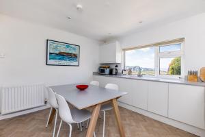 a white kitchen with a table and chairs at Bella Vista in Polzeath