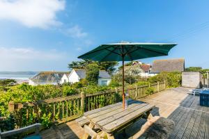 a wooden table with an umbrella on a deck at Bella Vista in Polzeath