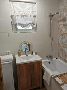W łazience znajduje się umywalka, wanna i lustro. w obiekcie Domek na Skarpie w mieście Miłomłyn