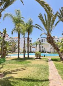 un parco con palme e una piscina di Nice Apartment in Marina Agadir ad Agadir
