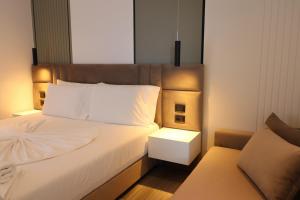 a bedroom with a white bed and a couch at ADMIRO Hotel in Ksamil