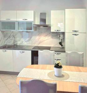 a kitchen with white cabinets and a table with a plant on it at Apartmani ANITA in Omiš