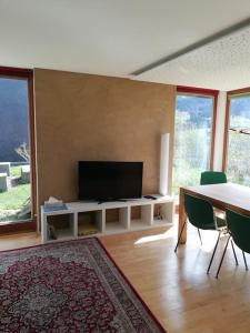 Urlaub in Alberschwende في البيرشوينده: غرفة معيشة فيها تلفزيون وطاولة وكراسي
