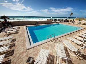 a swimming pool with lounge chairs and the beach at Emerald Isle fort Walton Beach 209 in Fort Walton Beach