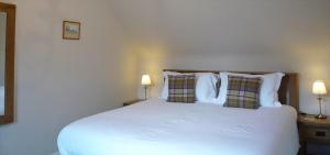 a bedroom with a large white bed with two lamps at Ivy Cottage Bed and Breakfast in Braemar