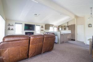sala de estar con muebles de cuero marrón y cocina en Stunning 4 Berth Lodge With Decking At Manor Park In Hunstanton Ref 23173k en Hunstanton