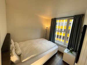um pequeno quarto com uma cama e uma janela em City Center Royal Pallace em Oslo