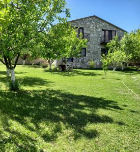 una casa de piedra en medio de un patio con árboles en Guest house Ijevan's Garden en Ijevan