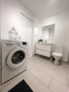 uma casa de banho branca com uma máquina de lavar roupa e um WC em City Center Royal Pallace em Oslo
