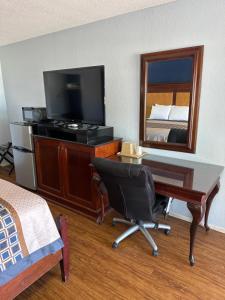 a hotel room with a desk and a bed and a mirror at Tanglewood Motel in Frederick