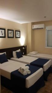 a bedroom with two beds with blue and white sheets at Summit Inn Hotel Barra Mansa in Barra Mansa