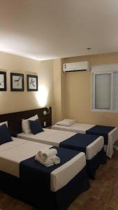 um quarto com três camas com lençóis azuis e brancos em Summit Inn Hotel Barra Mansa em Barra Mansa
