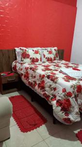 a bedroom with a bed with red flowers on it at Pousada do Sossego in Extrema