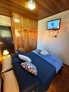 um quarto com 2 camas e uma televisão de ecrã plano em Hospedagem Vó Rosa em Monte Verde