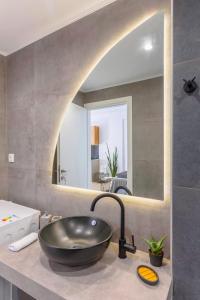uma casa de banho com um lavatório preto e um espelho em El mare em Ierápetra