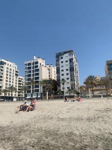 een groep mensen op een strand met gebouwen bij LA SANADORA in Almería