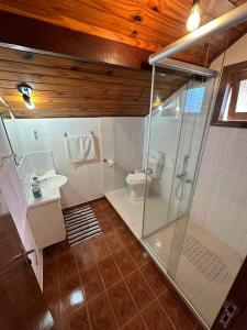uma casa de banho com uma cabina de duche em vidro e um WC. em Hospedagem Vó Rosa em Monte Verde