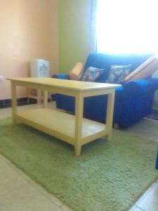 3Dee Apartment, Secure with Unlimited Wifi في كيزيمو: طاولة قهوة في غرفة معيشة مع أريكة زرقاء