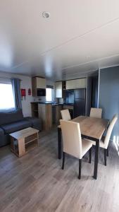 a living room with a table and chairs and a kitchen at Mobil-home Loic camping les Dunes de Contis in Saint-Julien-en-Born