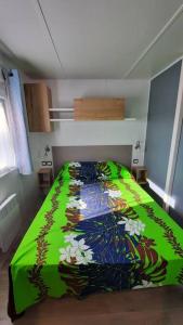 um quarto com uma cama com um edredão colorido em Mobil-home Loic camping les Dunes de Contis em Saint-Julien-en-Born