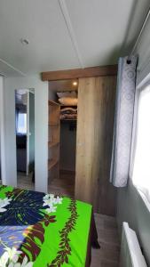 a bedroom with a green bed and a closet at Mobil-home Loic camping les Dunes de Contis in Saint-Julien-en-Born