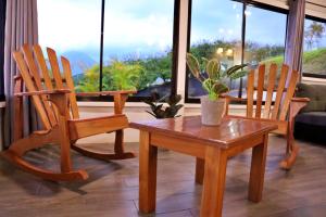 two wooden chairs and a table in a living room at Love Cabin - Arenal Volcano & Lake views in El Fosforo