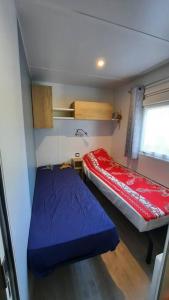 Cette petite chambre comprend 2 lits et une fenêtre. dans l'établissement Mobil-home Loic camping les Dunes de Contis, à Saint-Julien-en-Born