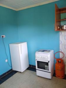 3Dee Apartment, Secure with Unlimited Wifi في كيزيمو: مطبخ ازرق مع ثلاجة وموقد