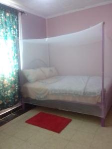 3Dee Apartment, Secure with Unlimited Wifi في كيزيمو: غرفة نوم بسرير وسجادة حمراء